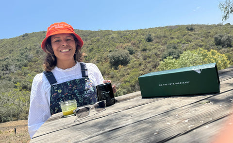 EDERRA Brand Ambassador Dr Gloria sitting on a bench outside with a biophotonic jar of EDERRA EMPWR+ and an EDERRA EMPWR+ Starter Kit Box