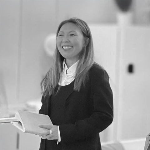 a black and white photo of EDERRA Regulatory Brand Advisor haeri roh-schmidt, PhD standing with a book giving a talk