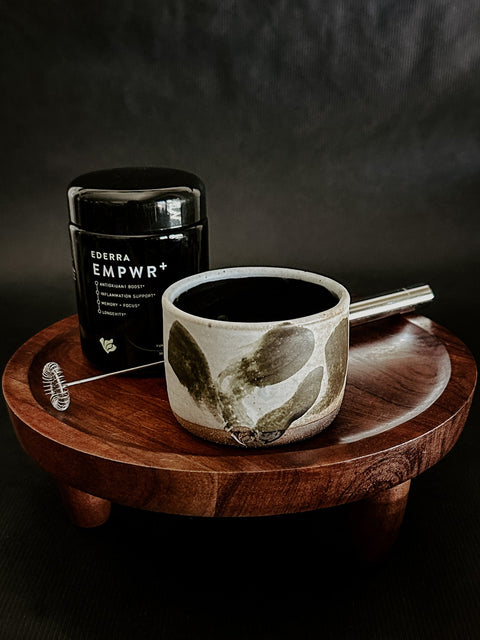 Ceramic LURRA mug with wooden coaster and black EMPWR+ Jar on dark background