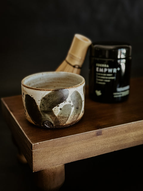 LURRA ceramic cup with black EMPWR+ jar and a whisk in the background