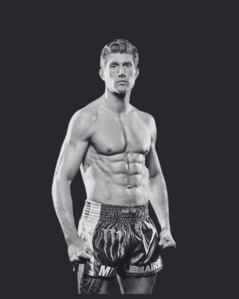A black and white photo of a muscular three times world champion of muay thai and EDERRA brand ambassador Mike Lemaire Standing with clenched fists and his shirt off