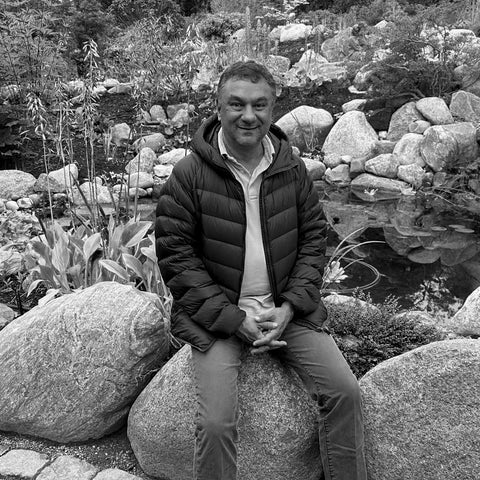A black and white photo of EDERRA R&D Brand Advisor Rahul Mehta, PhD sitting on a rock 