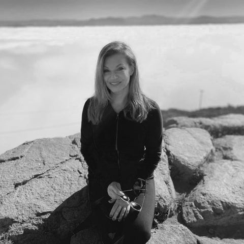 a Black and white image of EDERRA Sales Brand Advisor Rena Cohen First sitting on a rock outside