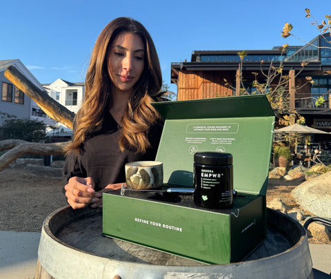A woman with a luxurious green box and biophotonic jar of EMPWR with a handcrafted ceramic LURRA cup and stainless steel frother